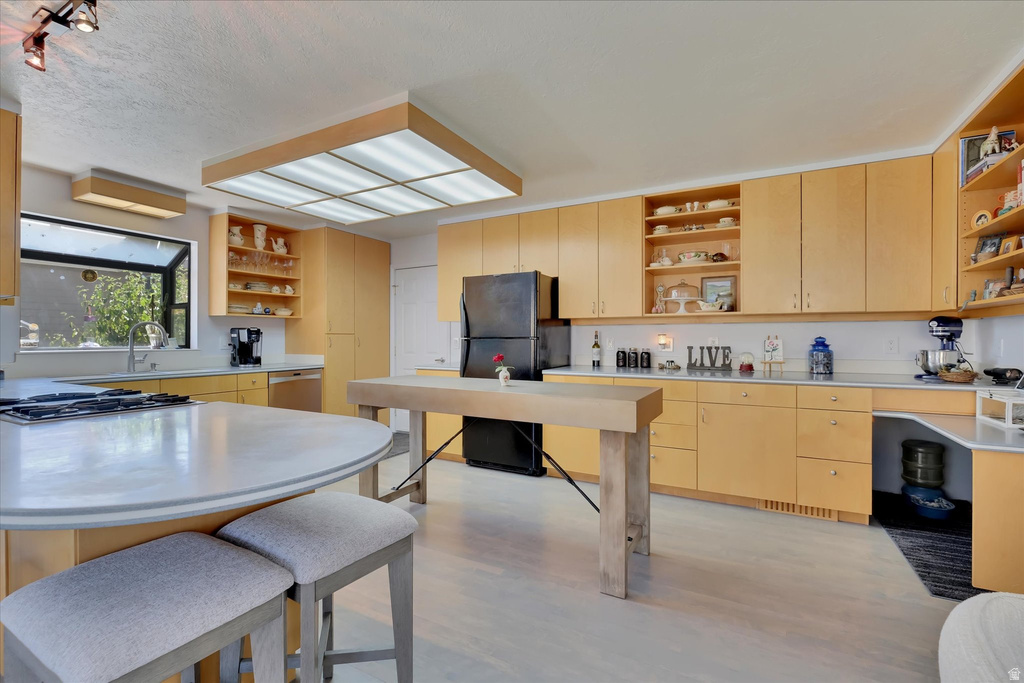 Kitchen featuring extensive light wood cabinetry, a large central island with integrated cooktop, a secondary butcher block island, and a skylight-style ceiling fixture