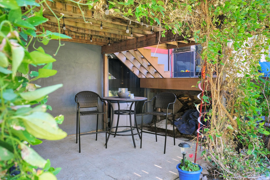 Outdoor patio area with a concrete slab, overhead wood pergola, and string lighting