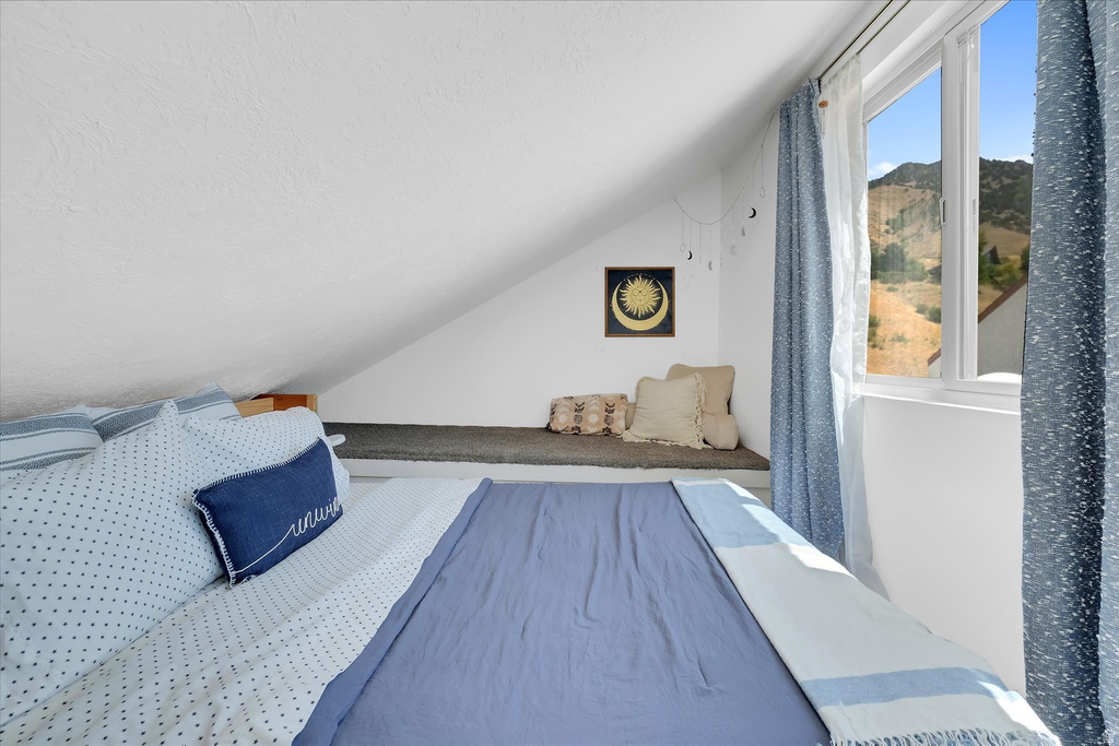 Sloped ceiling room featuring a large window, a built-in window seat, and mountain scenery