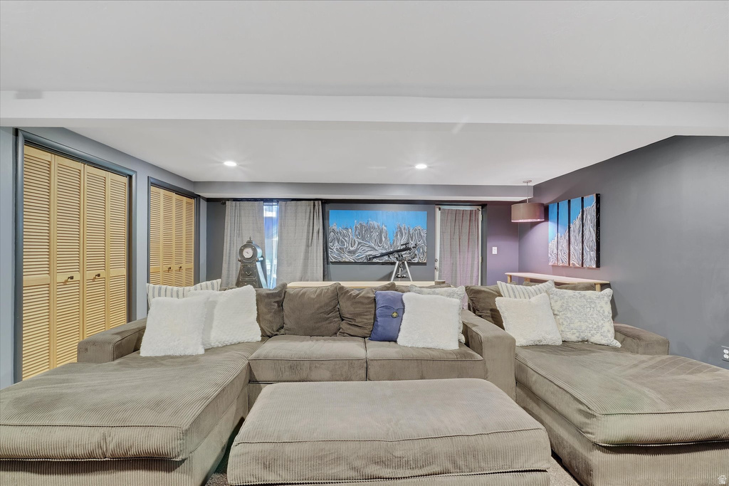 Recessed lighting illuminates this space featuring louvered bi-fold closet doors, a built-in wall shelf, and curtained windows