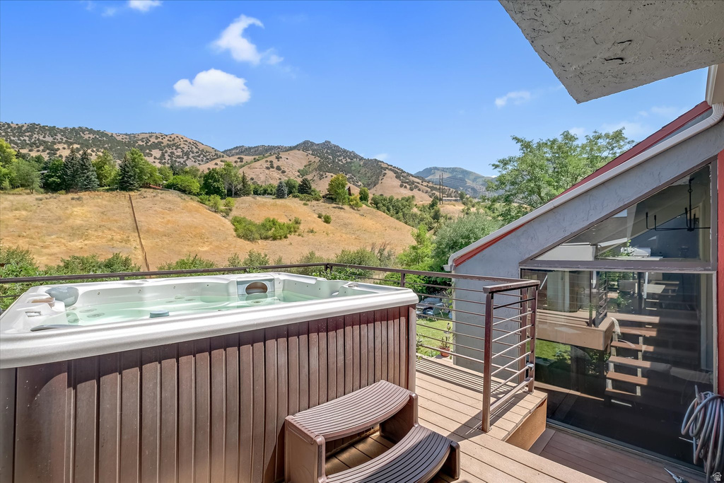 Outdoor deck featuring a built-in hot tub, cable railing, and a sloped roofline