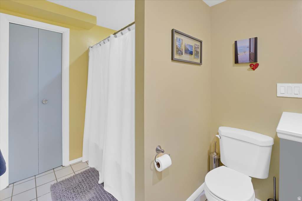 Bathroom featuring a white toilet, tile flooring, and a shower with a white curtain
