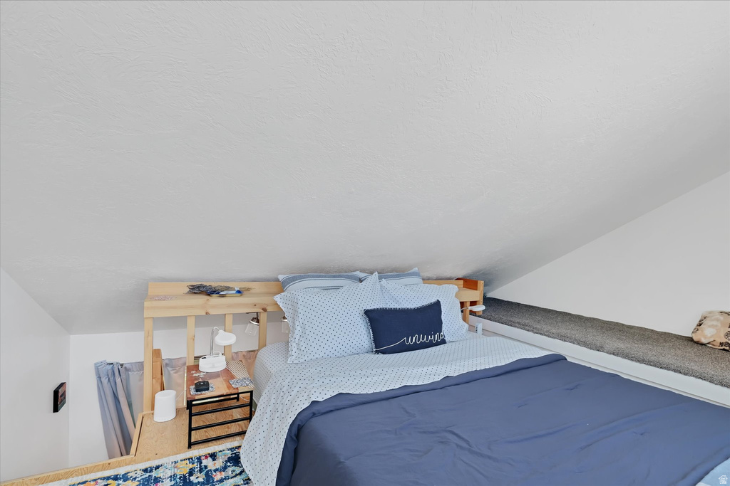 Loft sleeping area featuring a built-in wooden bed frame, sloped ceiling, and an integrated carpeted bench