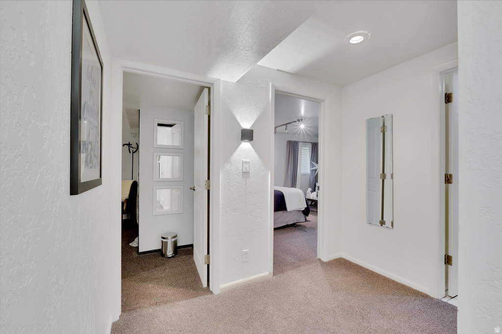 Carpeted hallway with white walls and overhead recessed lighting