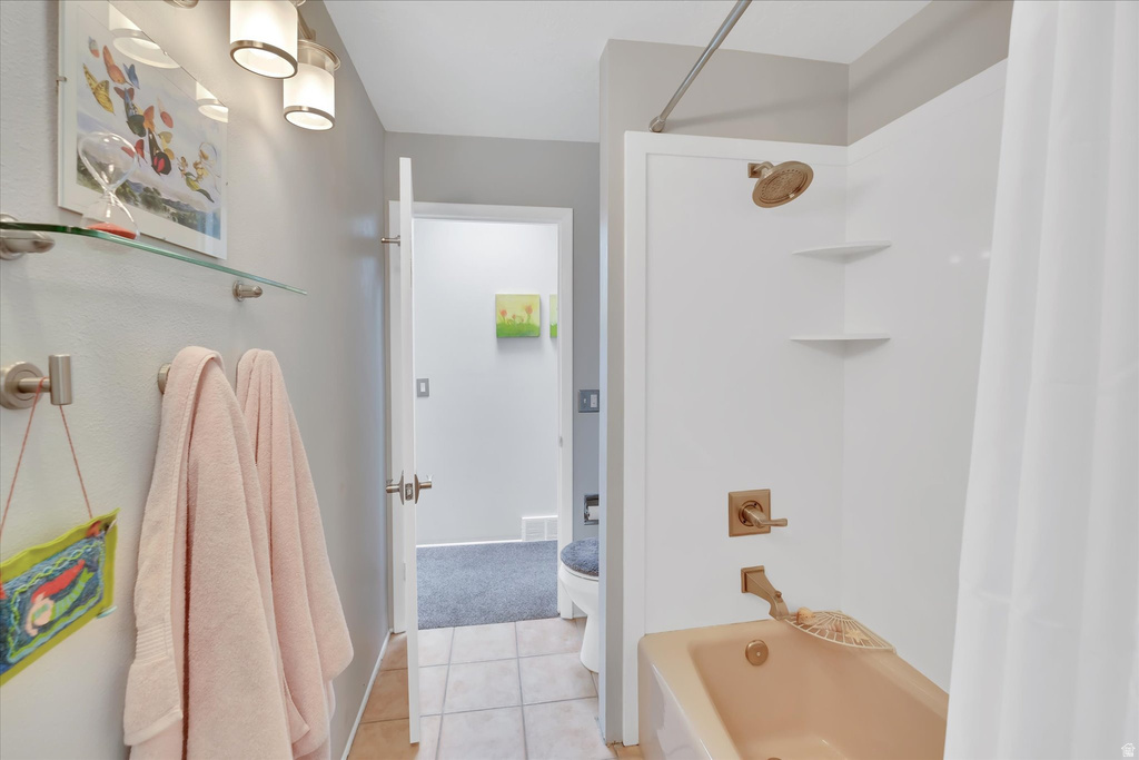 Bathroom featuring a full shower/tub combination with gold-toned fixtures and a white surround