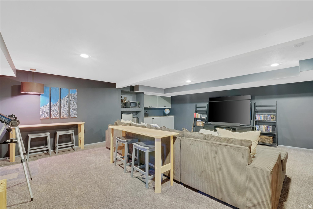 Finished lower level featuring recessed lighting, plush carpeting, a built-in media center, and a dedicated bar area with cabinetry and shelving