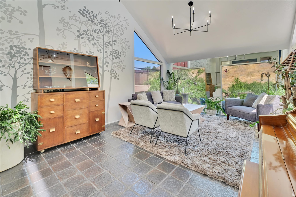Sun-filled interior space featuring high vaulted ceilings, large picture windows, and dark square tile flooring