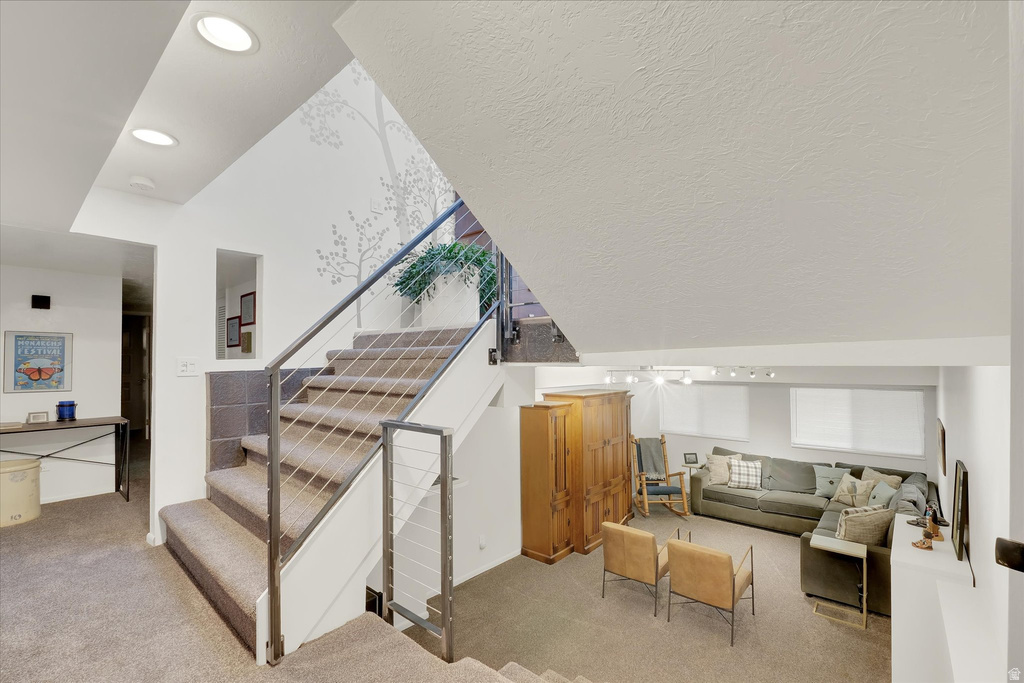 Multi-level interior featuring carpeted stairs with cable railings, recessed lighting, and a lower-level living area with windows
