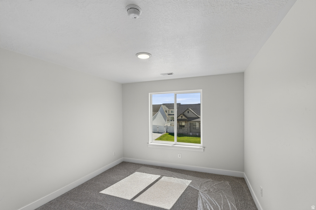 Bright interior room featuring a large window, recessed ceiling lighting, and textured carpeting
