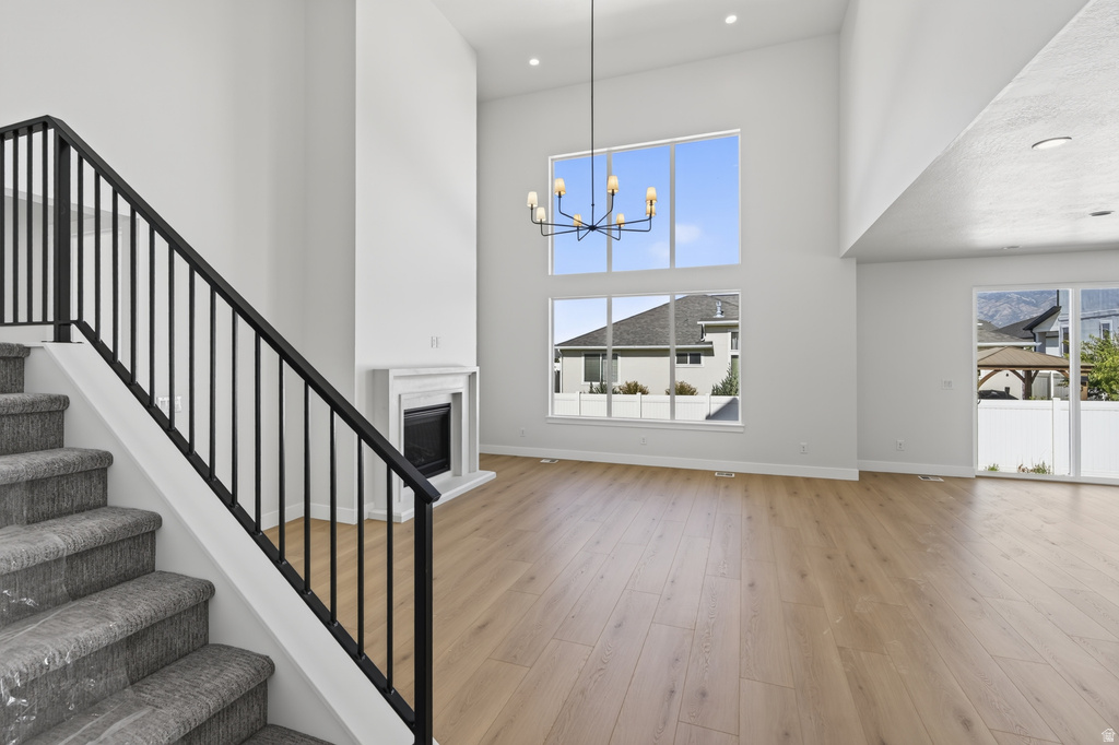 Two-story living area with wood-finish flooring, a contemporary fireplace with a white mantel, and extensive window-frontage