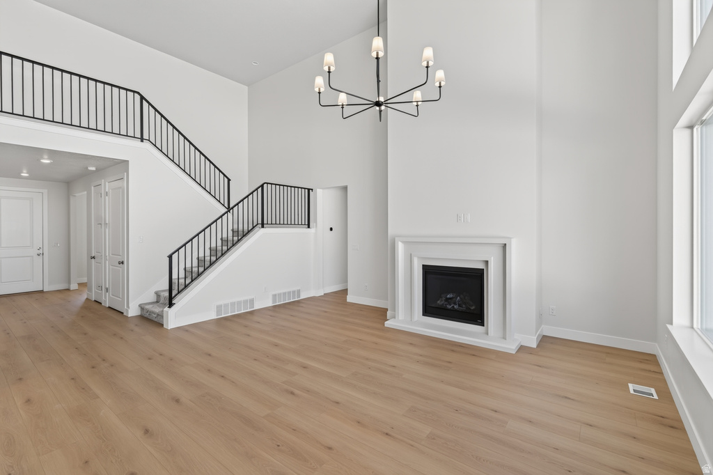 Spacious room featuring high ceilings, wood-finish flooring, and a contemporary fireplace with a classic surround