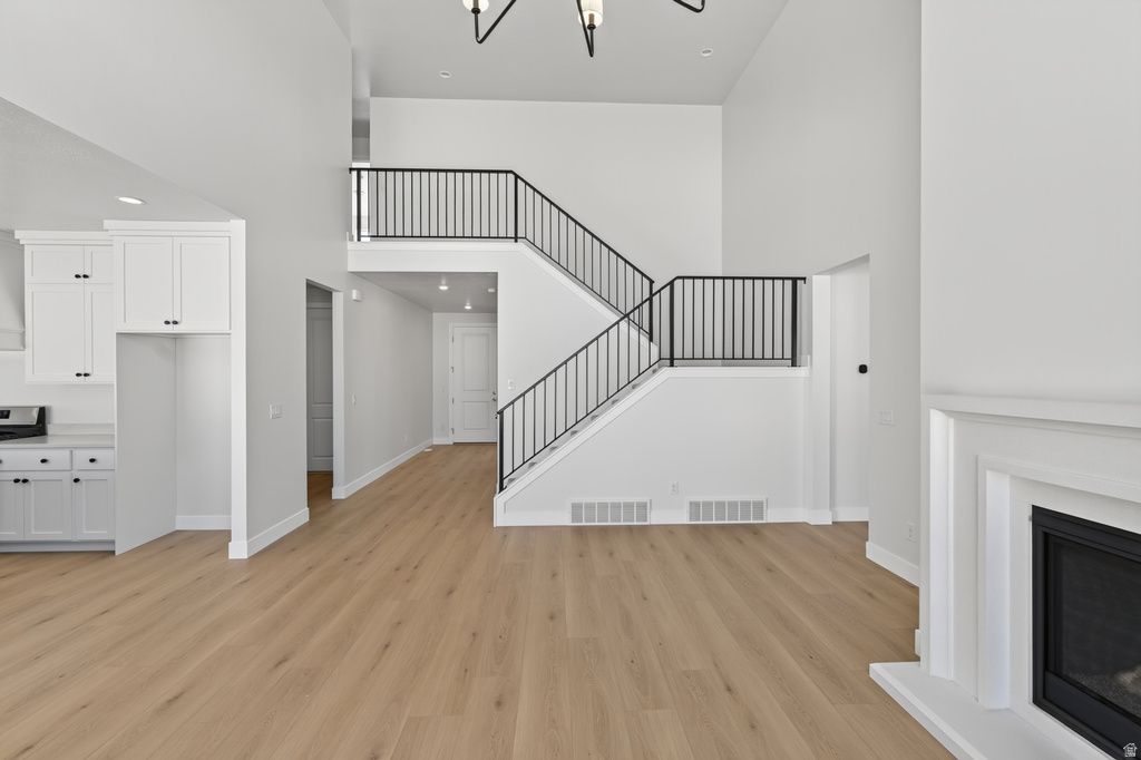 Spacious open-concept living area featuring high ceilings, wood-finish flooring, and a contemporary fireplace with white mantel