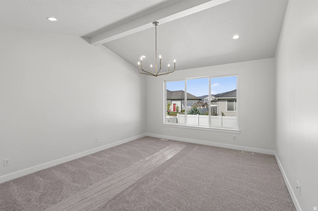 Spacious room featuring vaulted ceilings with a decorative beam, recessed lighting, and a contemporary chandelier