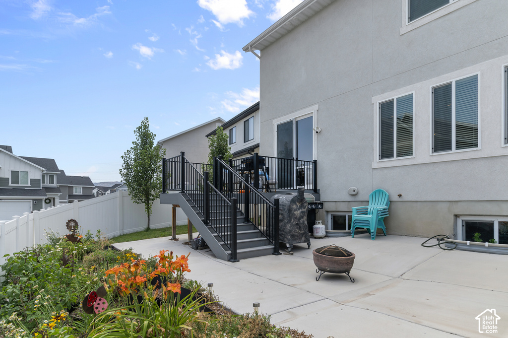Outdoor patio space featuring a multi-level deck with black railings, a concrete patio, and garden landscaping