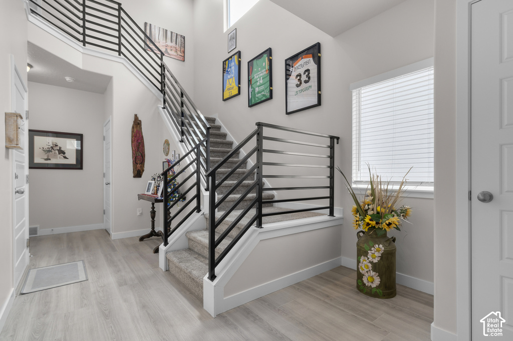 Two-story entryway featuring modern horizontal metal railings and light wood-finish flooring