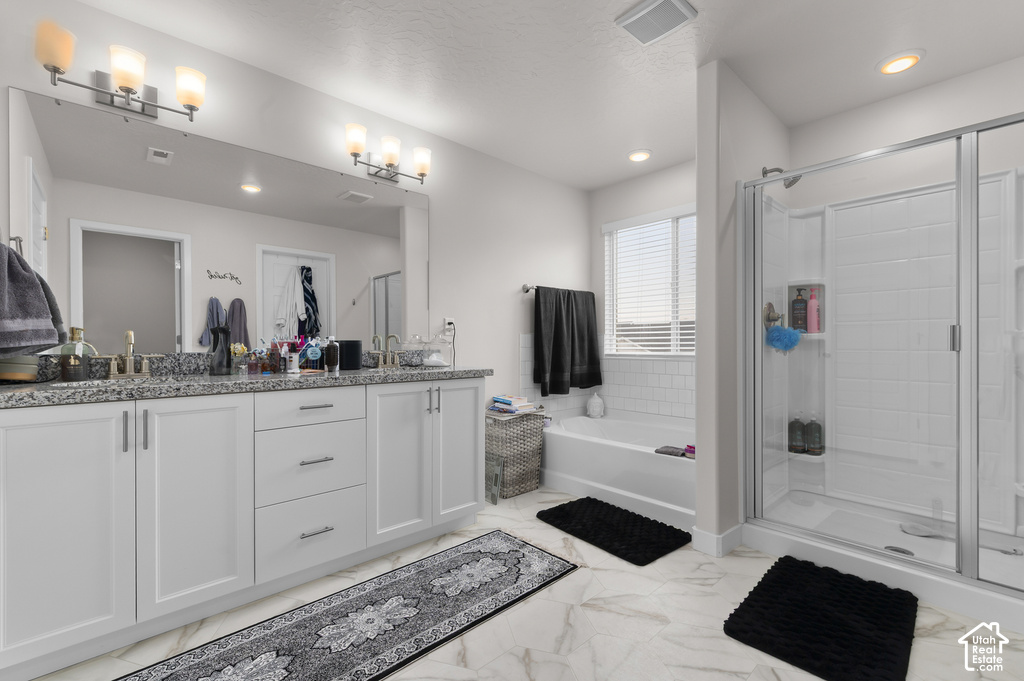 Spacious bathroom featuring a double vanity with stone countertops, a full-width mirror, and two contemporary light fixtures
