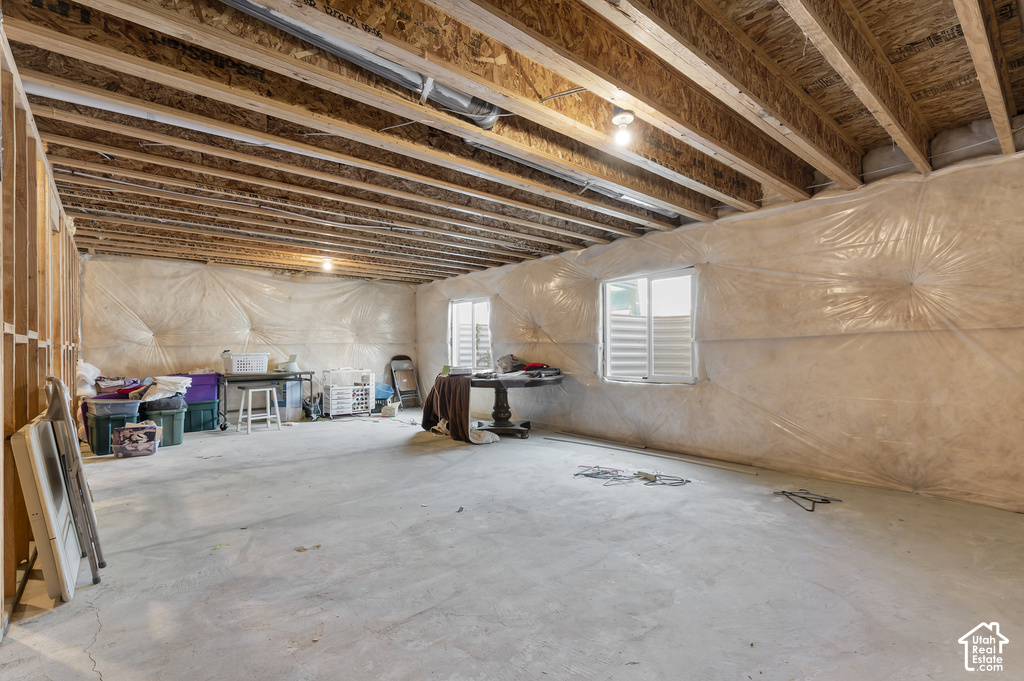Unfinished basement offering exposed wood ceiling joists, concrete flooring, and multiple window openings