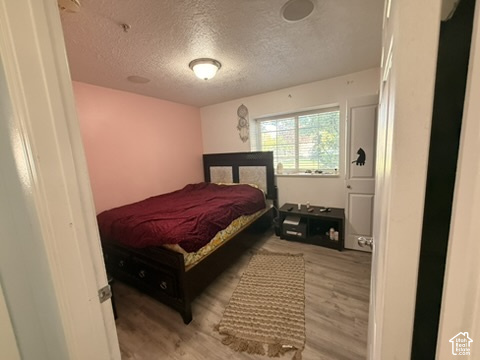 Room featuring wood-finish flooring, a contemporary ceiling light fixture, and a window with blinds
