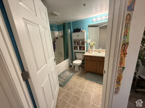 Bathroom featuring a single vanity with wood-finish cabinetry, a built-in bathtub with shower, and tile flooring