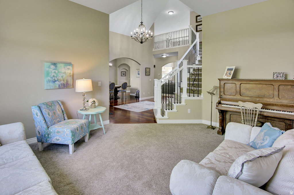 Vaulted ceilings with a chandelier, carpet flooring, a multi-level staircase with white railing and black spindles, and arched doorways