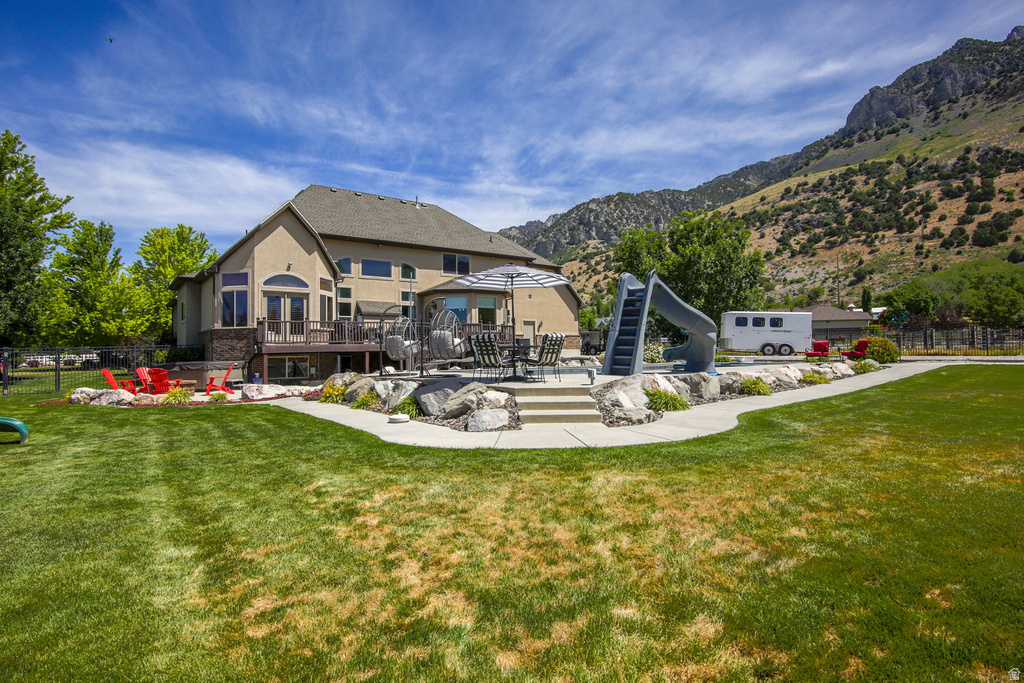 Expansive rear yard featuring a large lawn, a multi-level deck, and a paved patio area