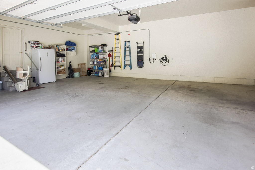 Spacious garage featuring a concrete floor, overhead lighting, and an automatic garage door opener