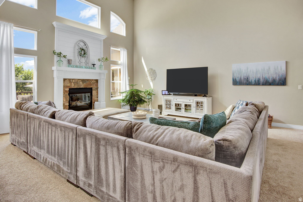 Living area featuring a stone-clad fireplace with a white mantel, high ceilings, large windows, and an entertainment console