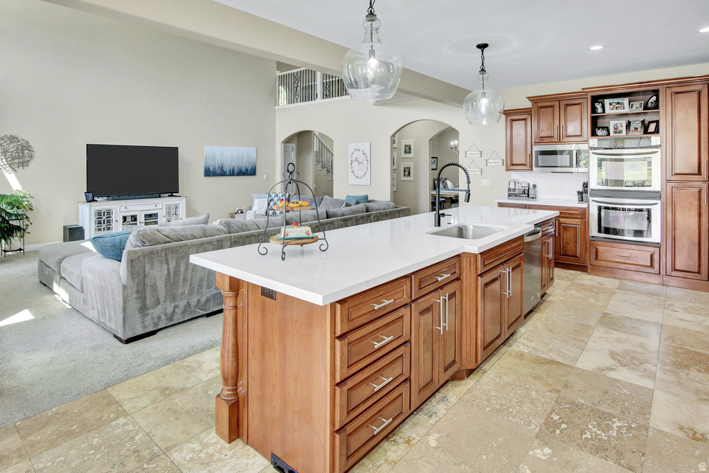 Spacious kitchen featuring a large central island with a white solid surface countertop, integrated sink with a matte black faucet, and wood cabinetry