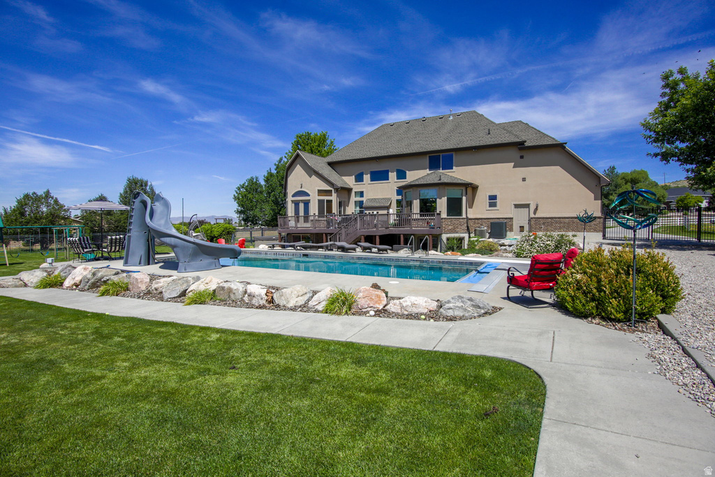 Expansive backyard featuring a large in-ground swimming pool, concrete patio, and a spacious rear deck