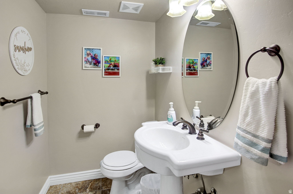 Pedestal sink with oil-rubbed bronze fixtures, oval vanity mirror, and coordinating towel and toilet paper holders