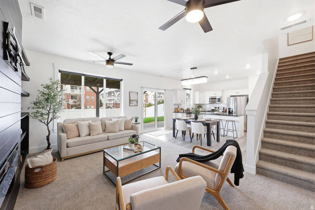 Open concept living area featuring light-toned carpeting and white walls