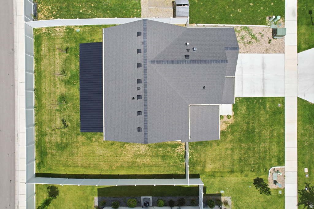 Property featuring a dark shingle roof, expansive green lawn, concrete driveway, and a fenced perimeter