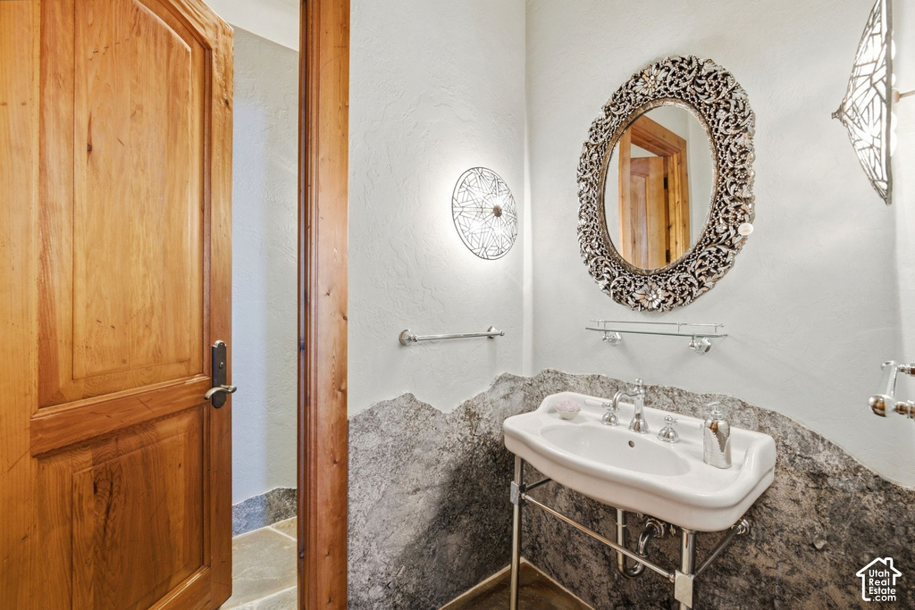 Pedestal sink with chrome fixtures and a decorative framed mirror