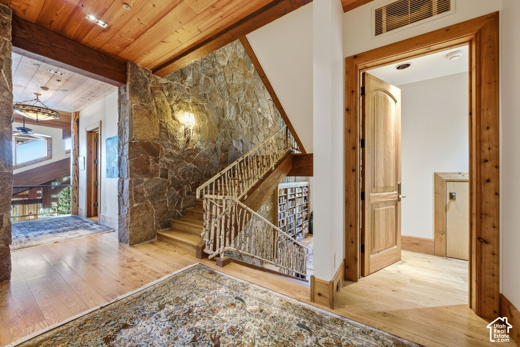 Stone accent wall featuring a wood-finish staircase with rustic twig-style railings
