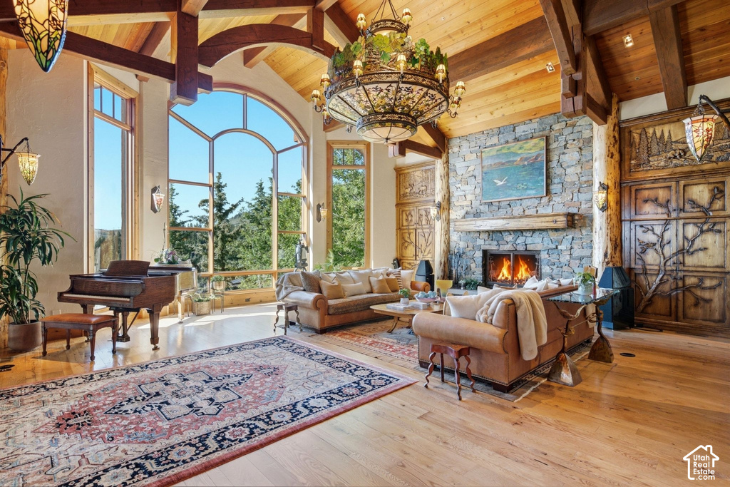 Grand living area featuring vaulted ceilings with exposed wood beams, a stone-clad fireplace with a wood mantle, and expansive arched windows