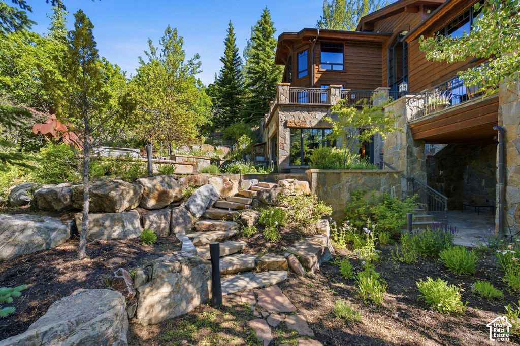 Multi-level stone retaining walls featuring natural rock steps, mature trees, and landscaping
