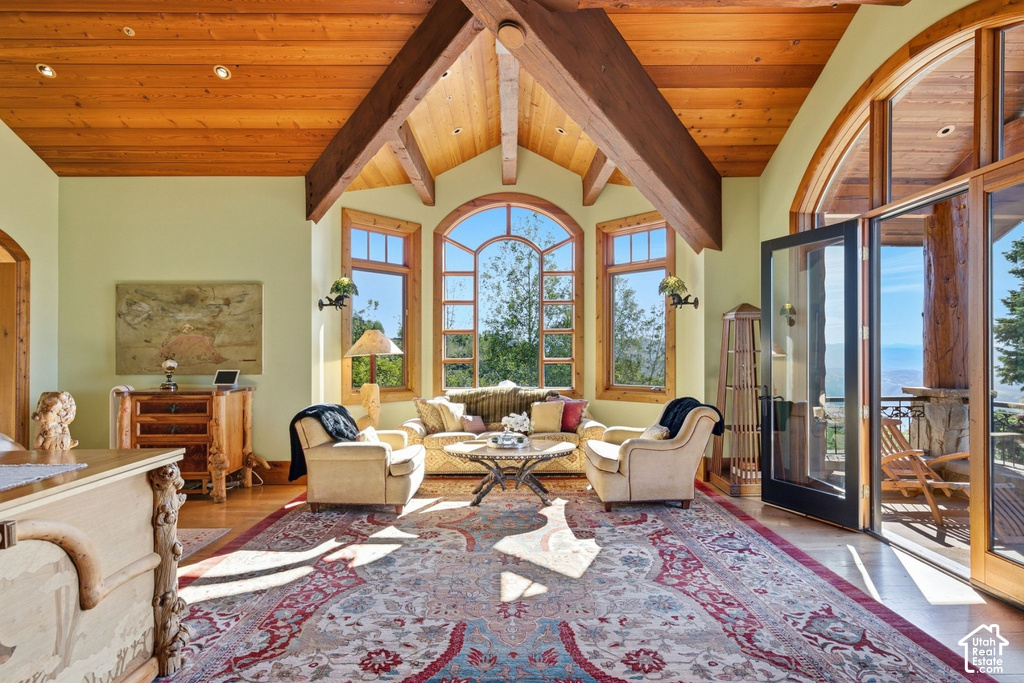 Bright room featuring a vaulted wood-paneled ceiling with exposed wood beams, arched windows, light-colored walls, wood-finish flooring, and a glass-paneled double door opening to an exterior space
