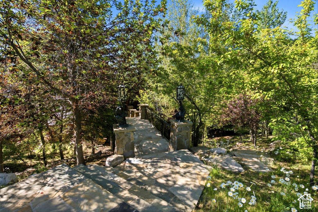 Terraced stone staircase featuring integrated stone posts with lanterns, surrounded by mature trees and natural landscaping
