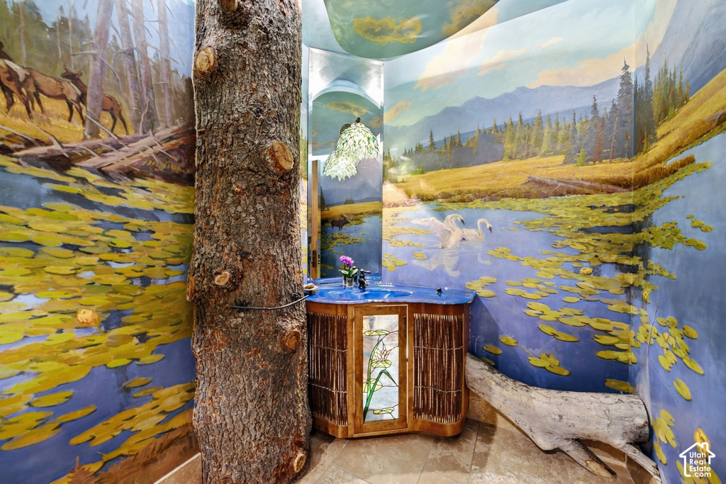 Bathroom featuring an integrated tree trunk, custom mural artwork, built-in wooden vanity with a blue countertop basin, and natural wood elements