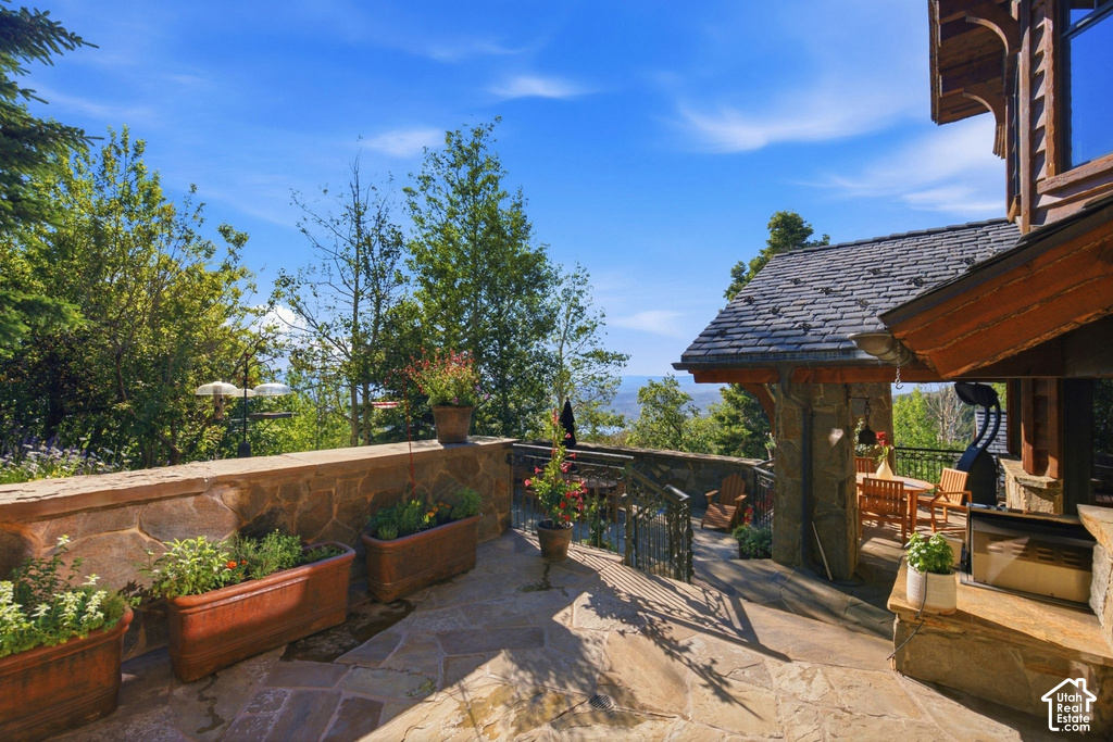 Outdoor stone patio with flagstone flooring, a stone retaining wall, and multiple planter boxes