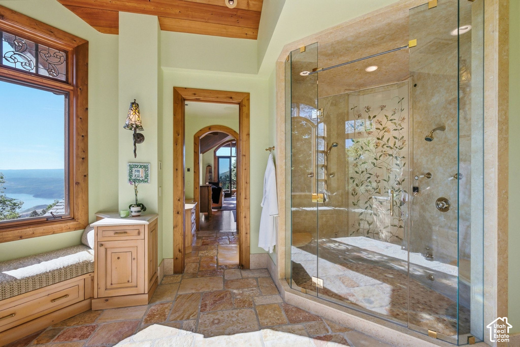 Spacious bathroom featuring a large glass-enclosed shower with multiple showerheads, stone-finish walls, and decorative glass panels