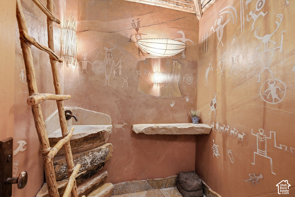 Custom bathroom with a stone basin sink, integrated faucet, and a decorative ladder accent