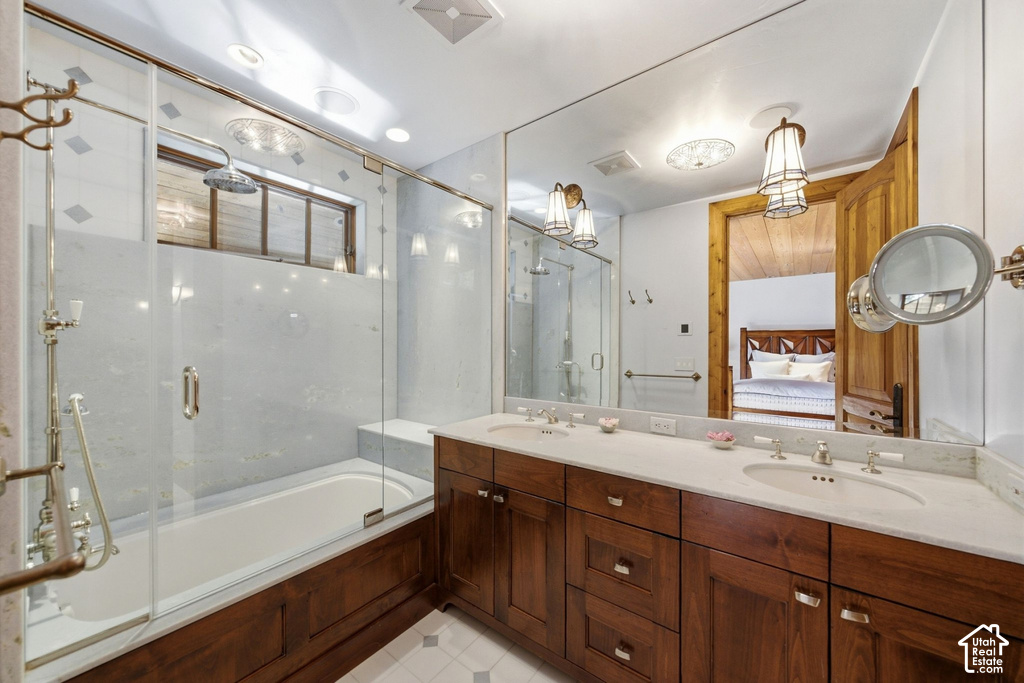 Bathroom featuring a double vanity with stone countertops, integrated sinks, and brass-tone fixtures