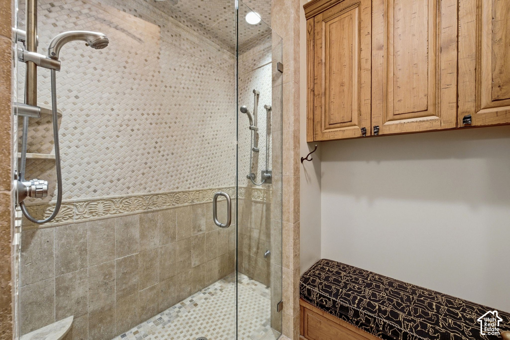 Glass-enclosed shower featuring a handheld showerhead and patterned tile work