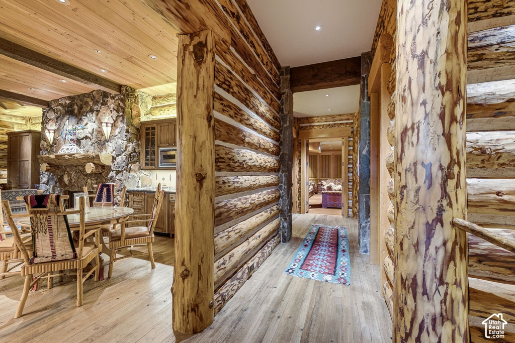 Log-hewn interior walls with exposed natural wood beams and light wood-finish flooring