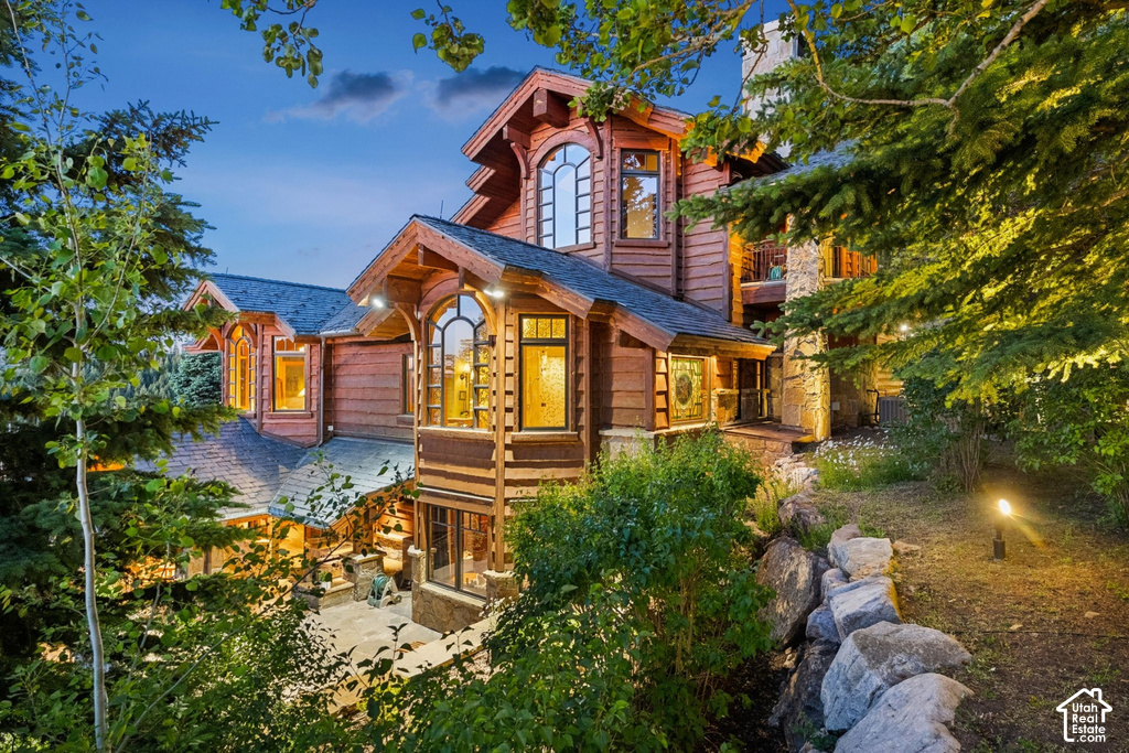 Multi-level wood-sided exterior featuring stone accents, gabled roofs, and arched windows