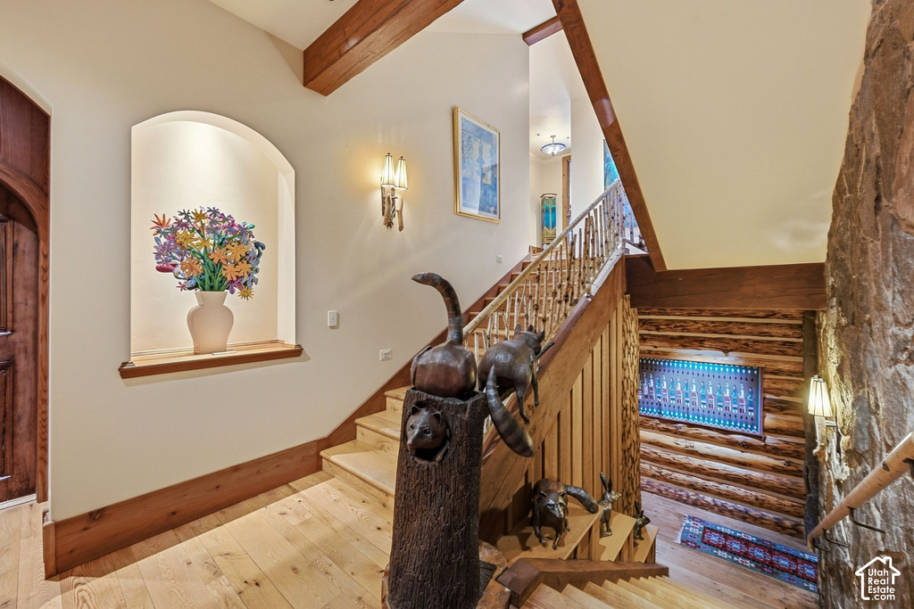 Staircase featuring wood-finish treads and risers, natural wood railings, and exposed wood ceiling beams