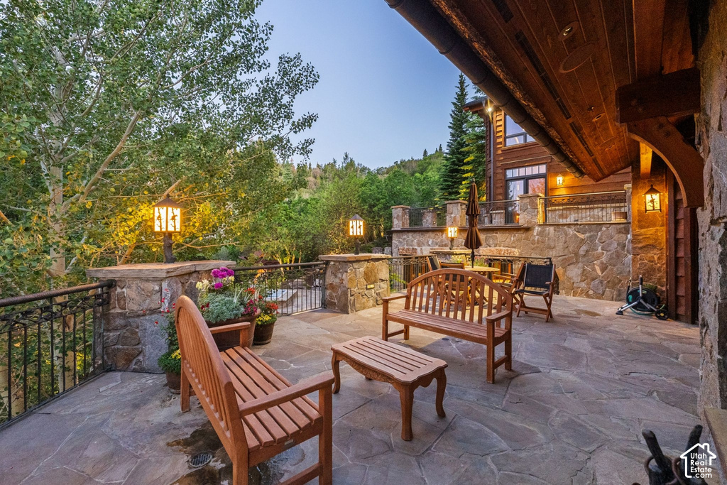 Expansive stone patio featuring a wrought iron railing, integrated stone walls, and permanent outdoor lighting fixtures