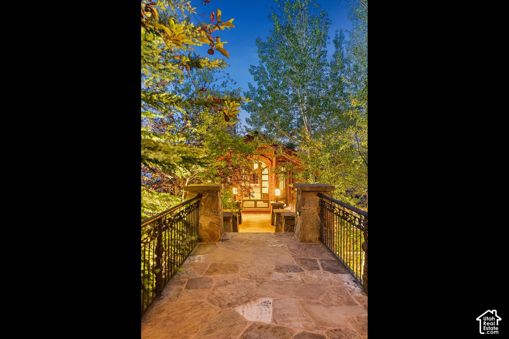 Stone paver walkway with wrought iron railings, leading to a wooden entrance