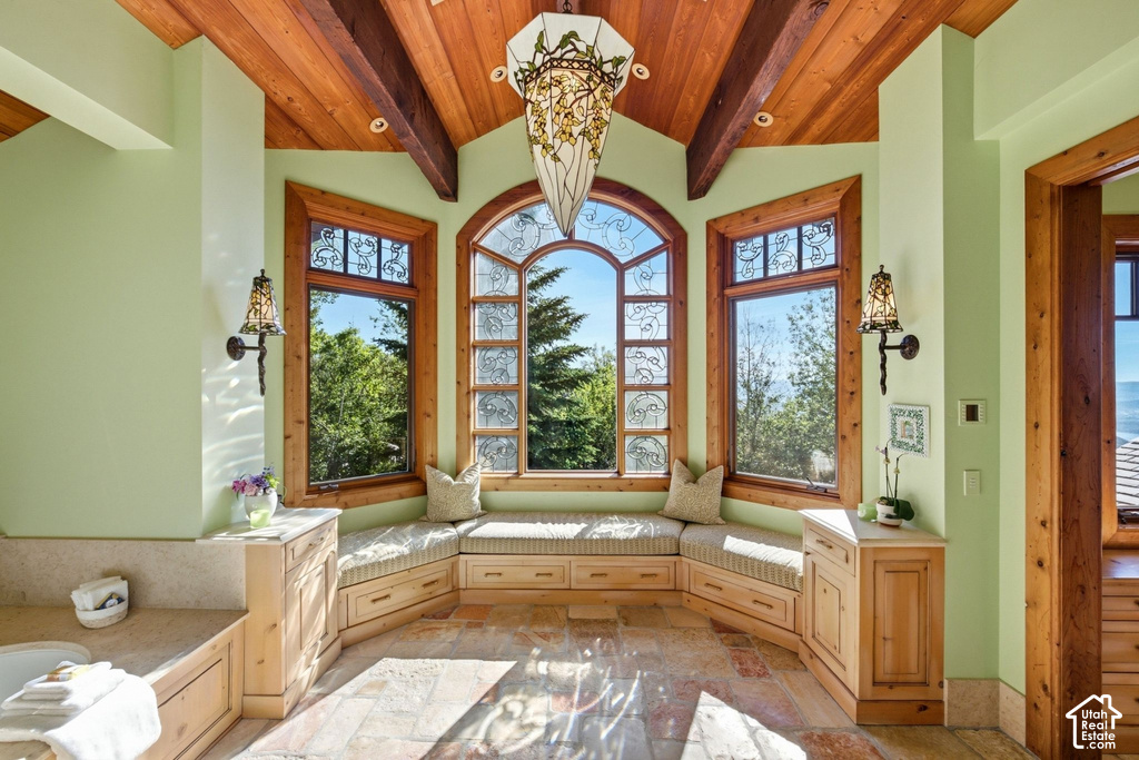 Spacious room featuring a vaulted wood-paneled ceiling with exposed beams, an arched window with decorative glasswork, and two additional windows with natural wood trim